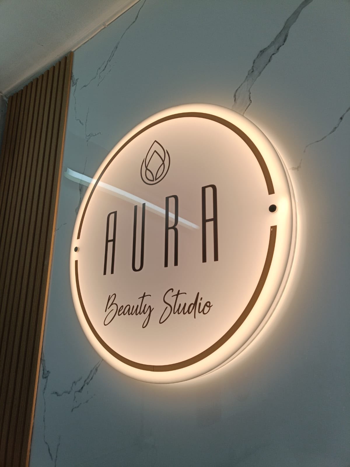 Cartel iluminado de Aura Beauty Studio en el estudio